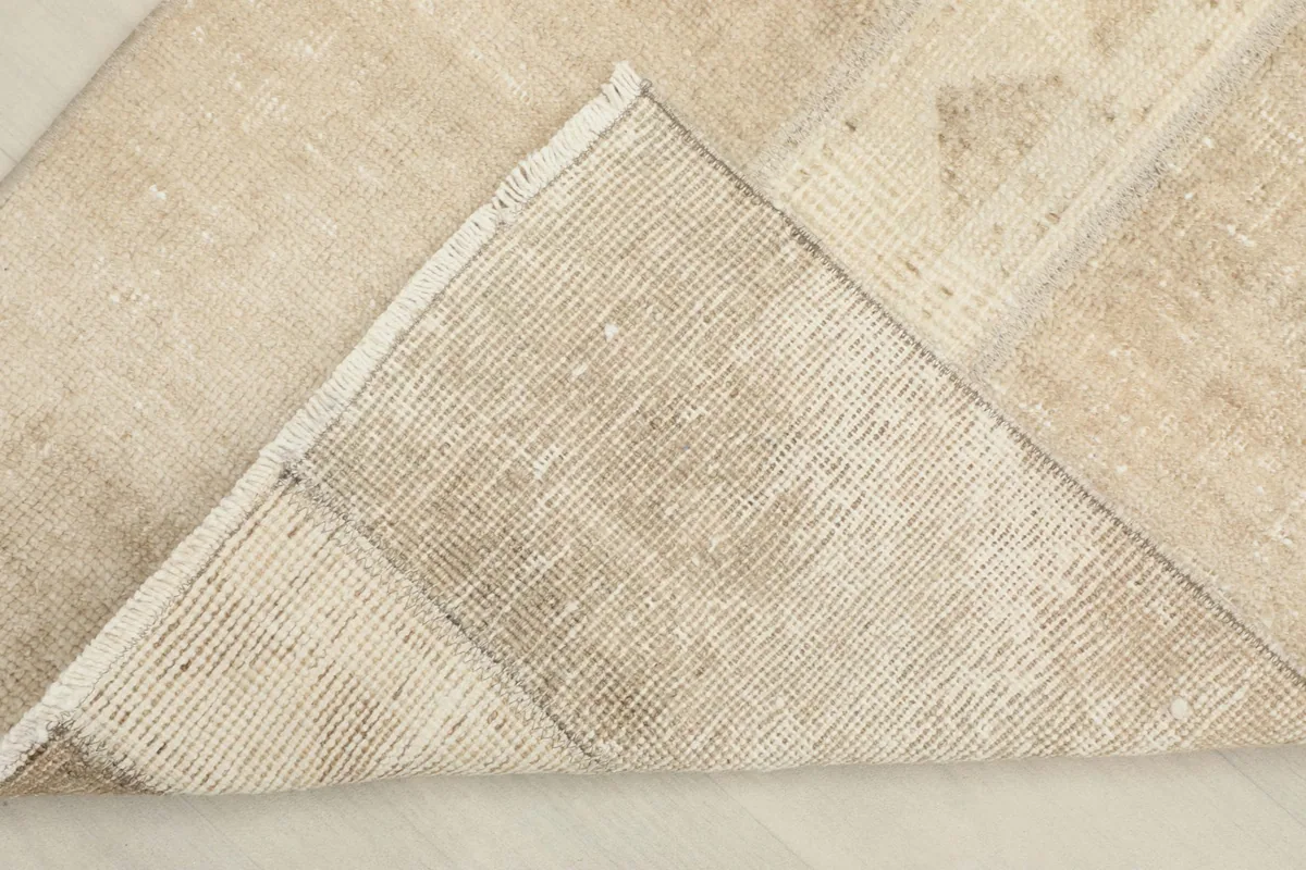 View of the back of the hand-knotted wool rug, revealing its cotton foundation and construction.