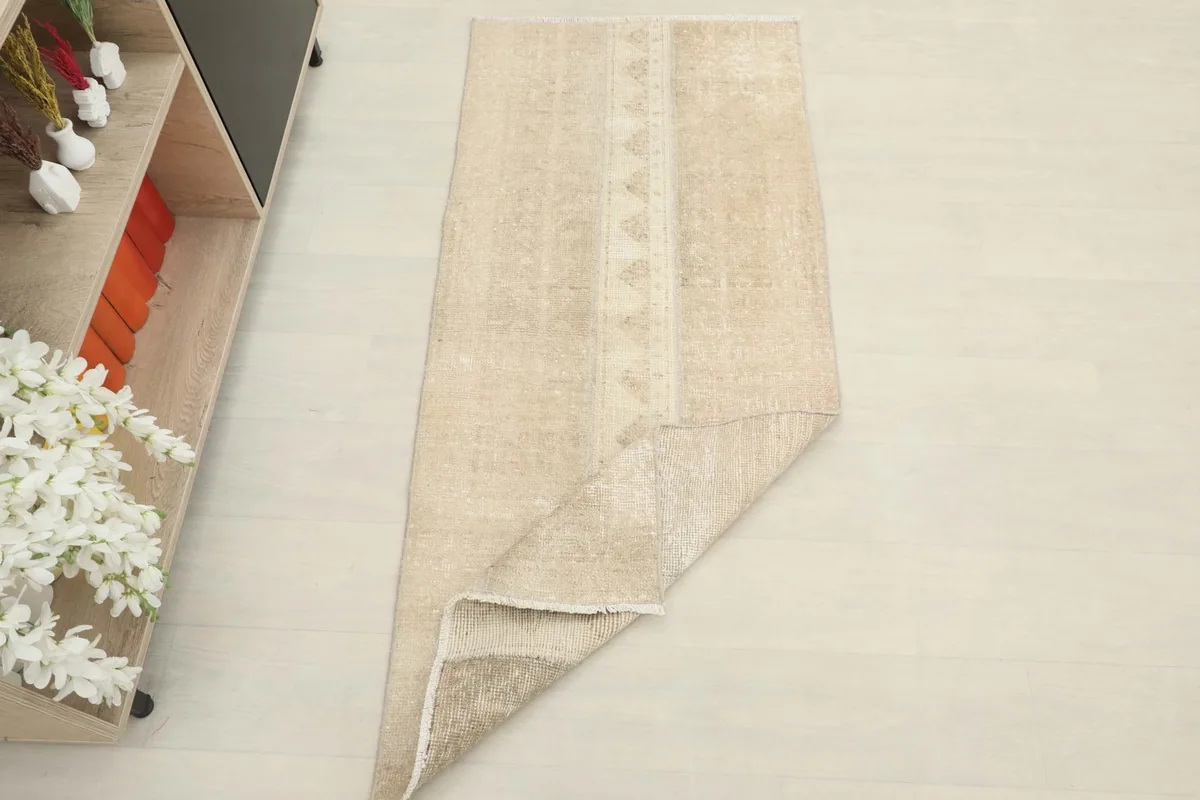 The tan vintage runner folded slightly to show its thickness and flexibility on the floor.