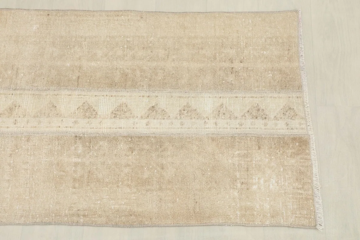 Overhead view showing one end of the tan vintage runner, highlighting the geometric design.
