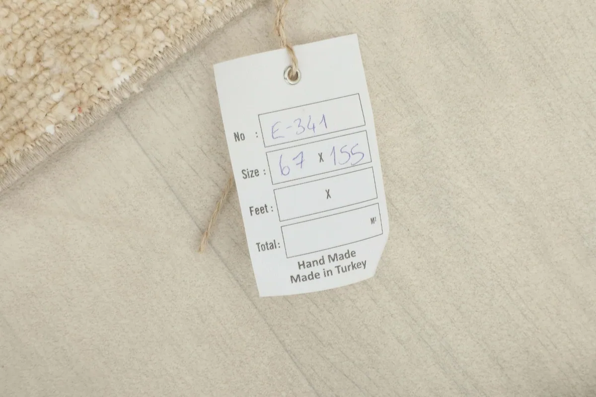 Close-up of the product tag showing the rug's size 67x155 cm and 'Hand Made in Turkey' details.