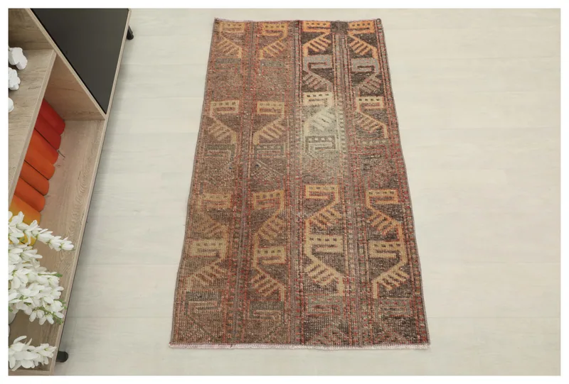 Full overhead view of the brown and rust geometric vintage Anatolian rug on a white floor