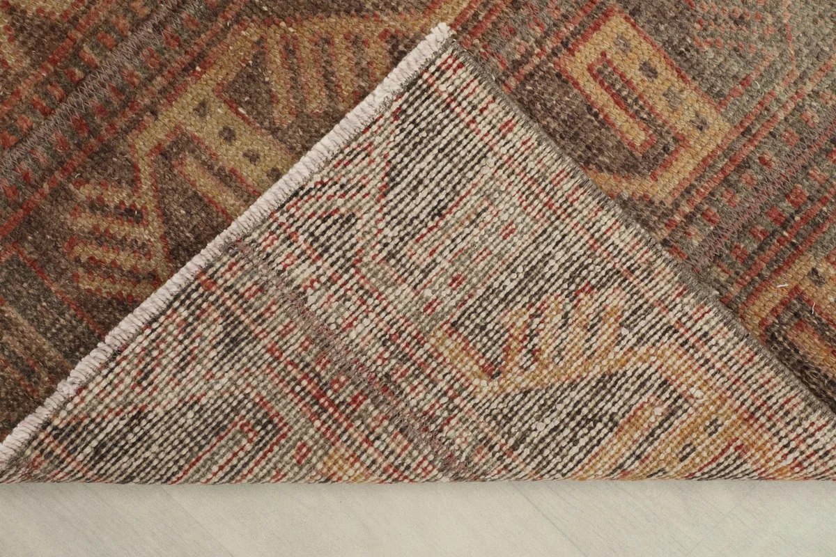 View of the back of the rug, folded to show the cotton foundation and knotting structure