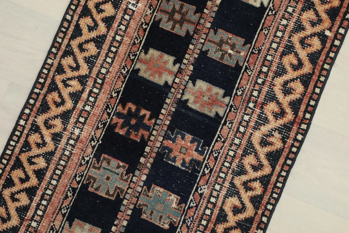 Close-up detail of the navy field with rust, beige, and gray tribal geometric motifs.