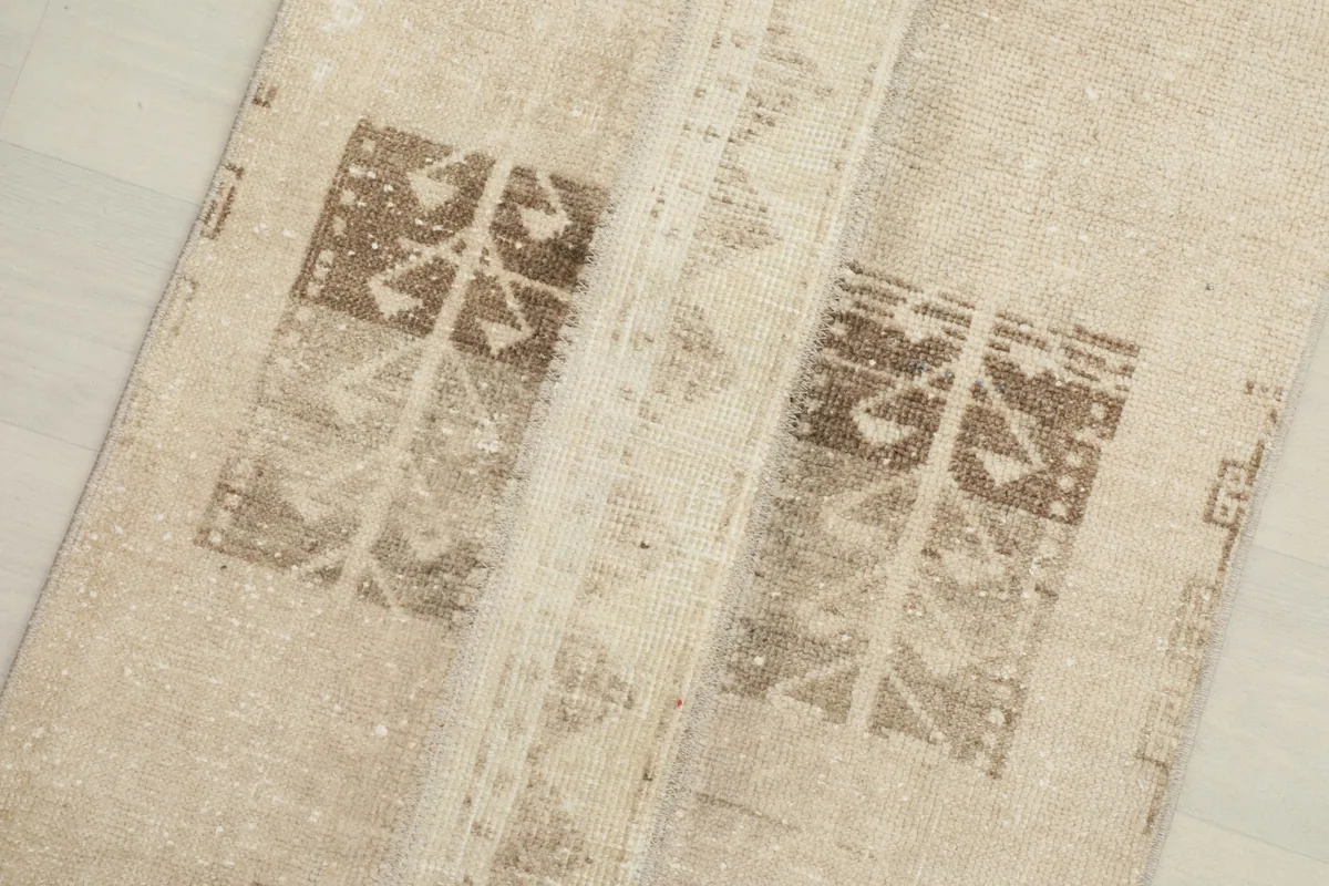Close-up view of the center geometric and tribal motifs in brown on the beige field.