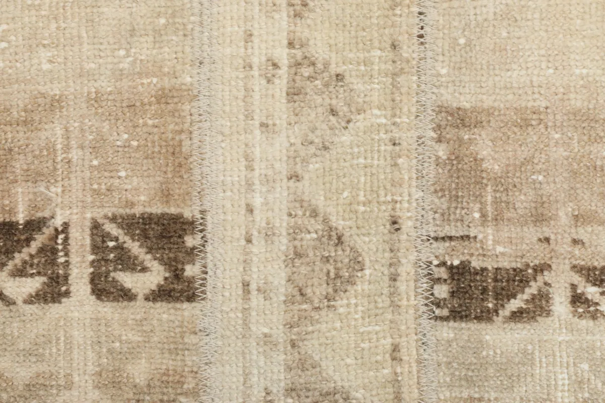 Detailed close-up of the distressed wool pile and a brown geometric pattern.