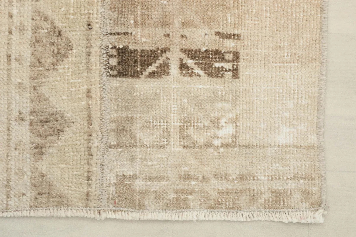 Close-up of the rug's short end, showing the low pile and a natural fringe.