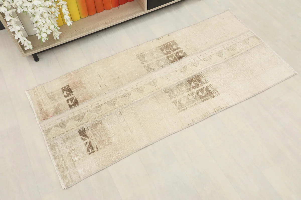 Slightly angled overhead view of the beige and brown vintage rug, showing its full length.
