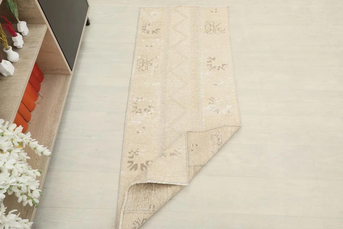The beige runner rug partially folded, illustrating its flexibility and thickness.