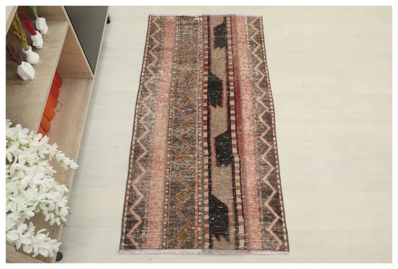 Full top view of the 2'2" x 4'3" rose, brown, and black geometric Anatolian rug on a white floor.