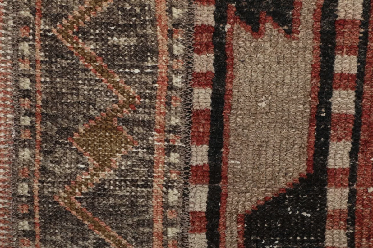 Detailed view of the hand-knotted wool pile and intricate tribal patterns on the rug.