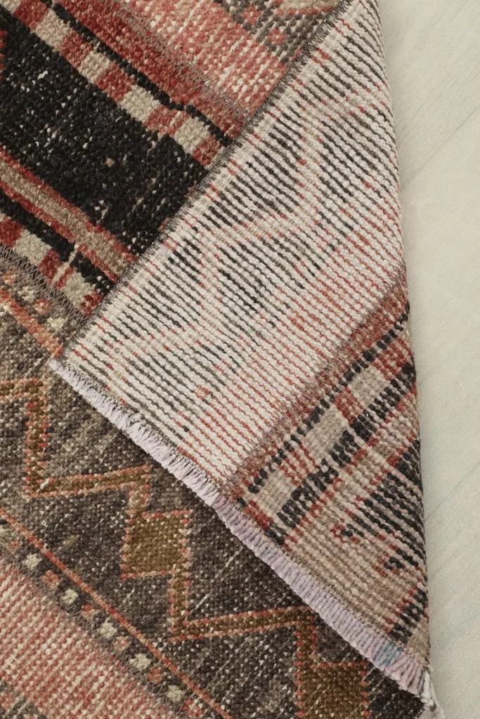 Corner folded back to reveal the cotton foundation and the reverse side of the hand-knotted rug.