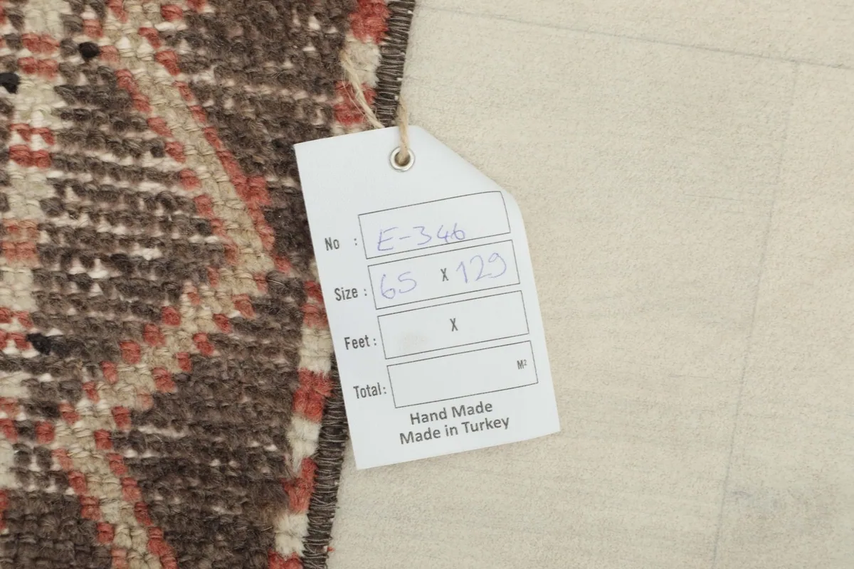 Close-up of the rug's back with a tag showing its origin as hand made in Turkey and size in centimeters.