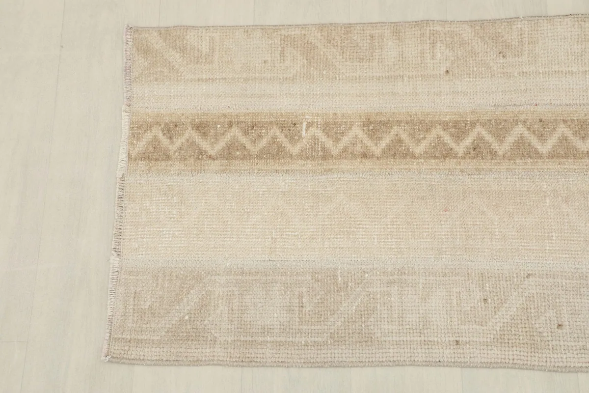 Close-up of the other end of the vintage rug, showing the wool pile and subtle motifs.