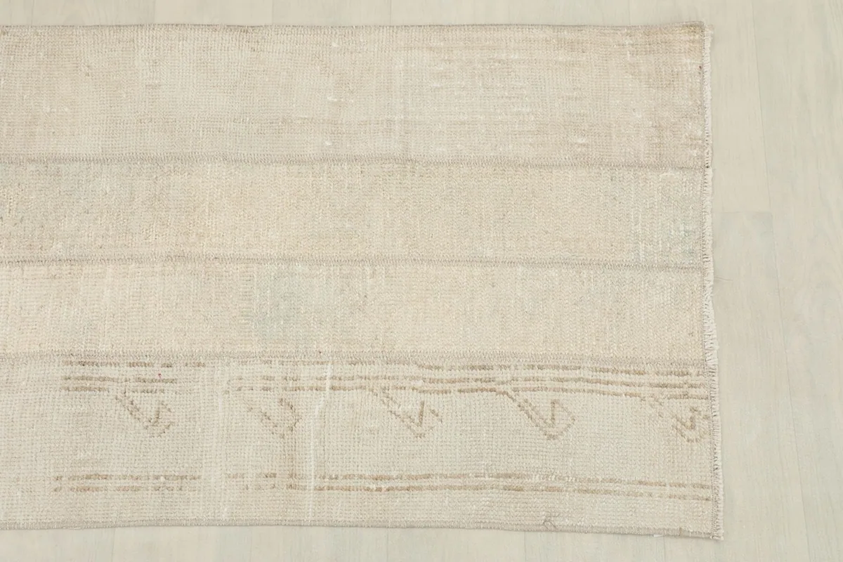 Detail view of one end of the rug, showing the subtle geometric lines and fringe.