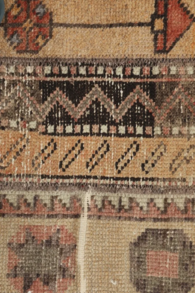 Detailed view showing the intricate tribal patterns and texture of the vintage rug