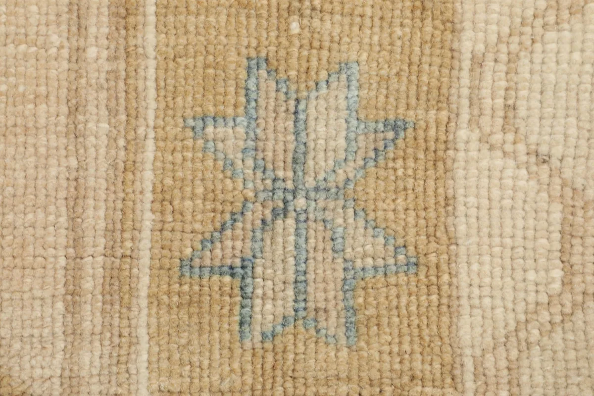 Detailed close-up of a light blue star-like geometric motif on the gold-toned pile.