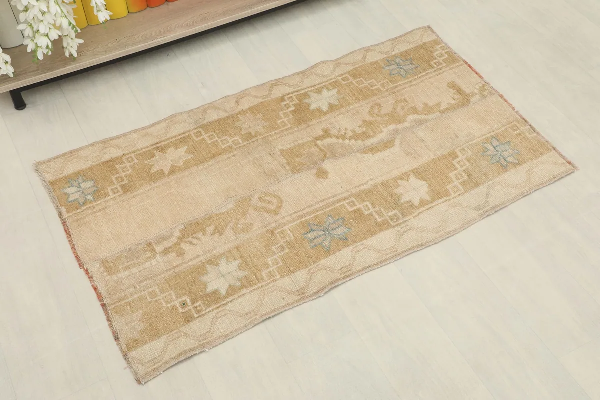 Overhead angled view of the small beige and gold vintage rug with geometric patterns.