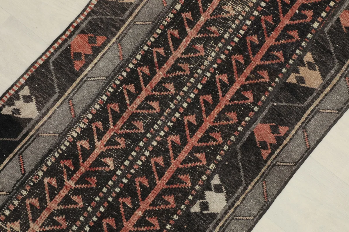Close-up of the rug's central design, highlighting black, rust, and gray motifs