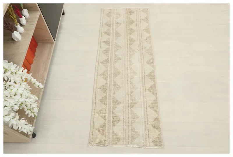 Full top view of the 1'8" x 4'8" beige and tan tribal geometric runner rug on a white background.