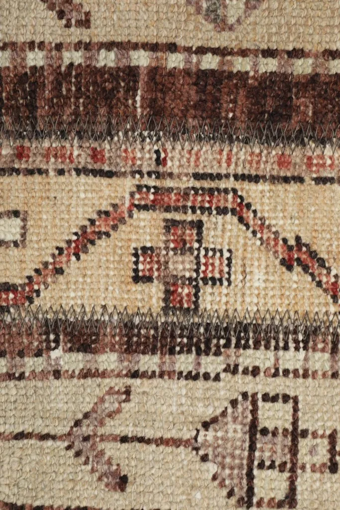 Detailed close-up of the hand-knotted wool pile, showing specific geometric motifs in brown and rust.