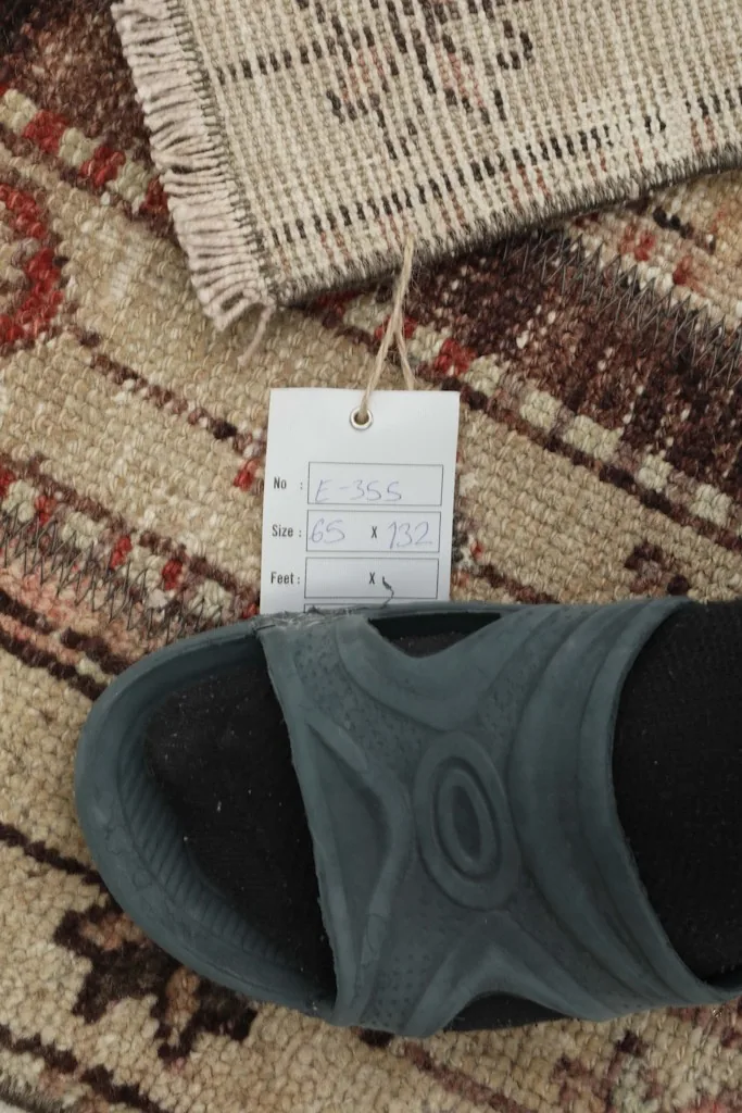 Close-up of the rug with a size tag and shoe for scale, showing the texture and pile.