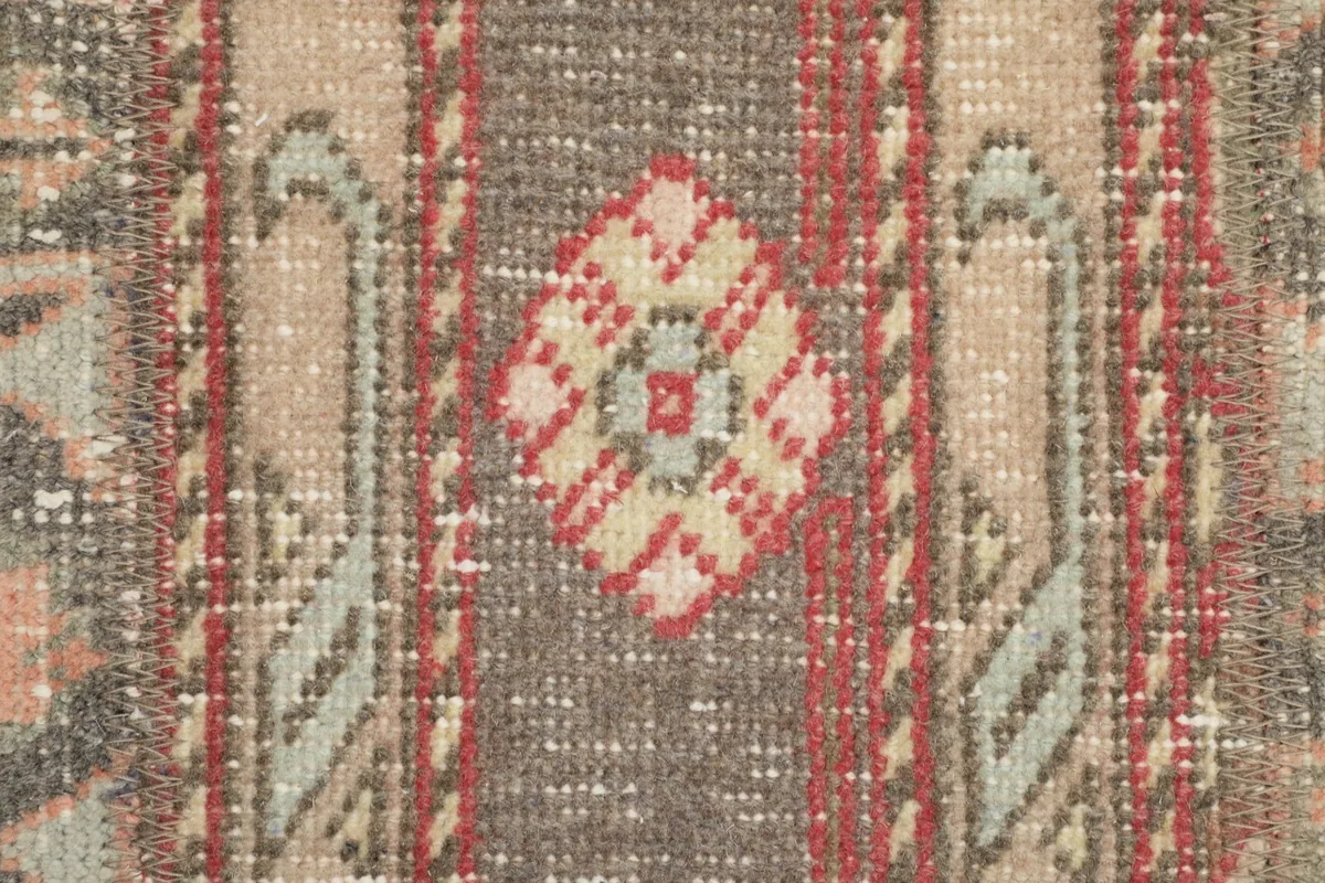 Detailed view of the rug's central tribal motif in rust, beige, and gray tones
