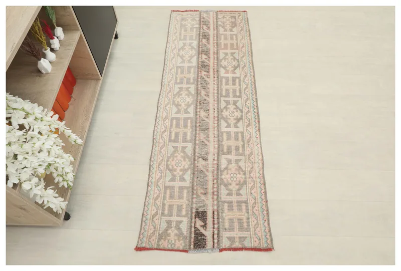 Full top view of the 1'11" x 5'7" gray and rose geometric Anatolian runner on a white background