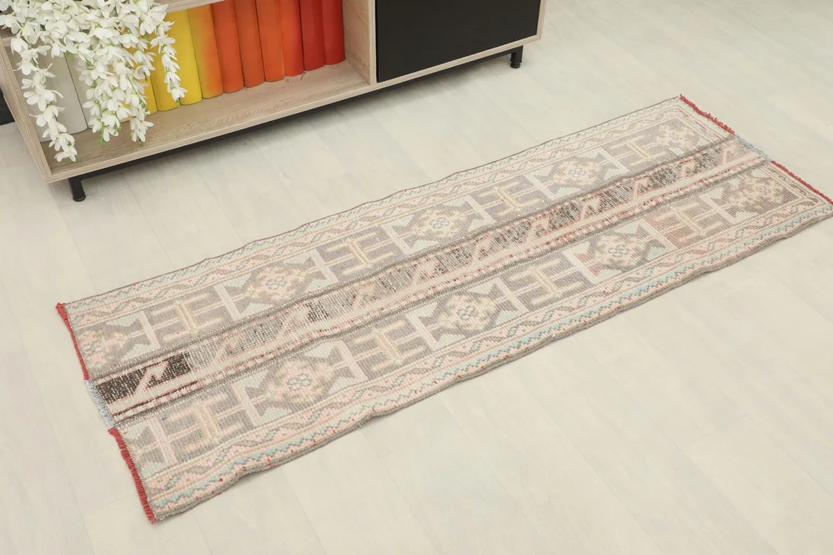 Overhead angled view of the gray and rose vintage runner in a room setting with a shelf
