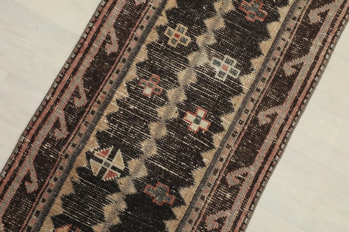 Close-up of the black field with beige and red geometric motifs on the hand-knotted rug