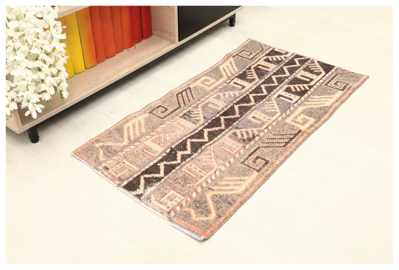 Full top view of the beige and brown tribal pattern vintage Anatolian rug on a light floor.