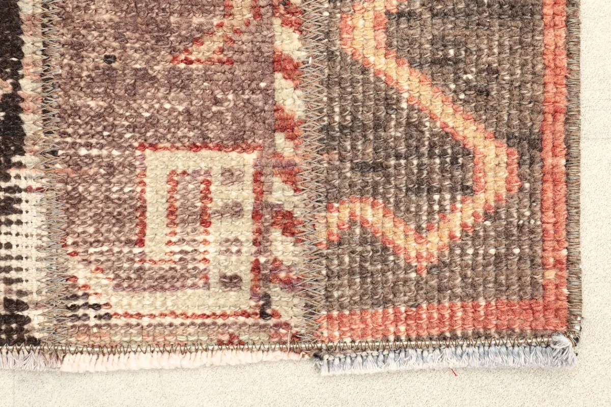 Close-up detail of the rug's edge, showing hand-knotted wool pile and subtle rust accents.