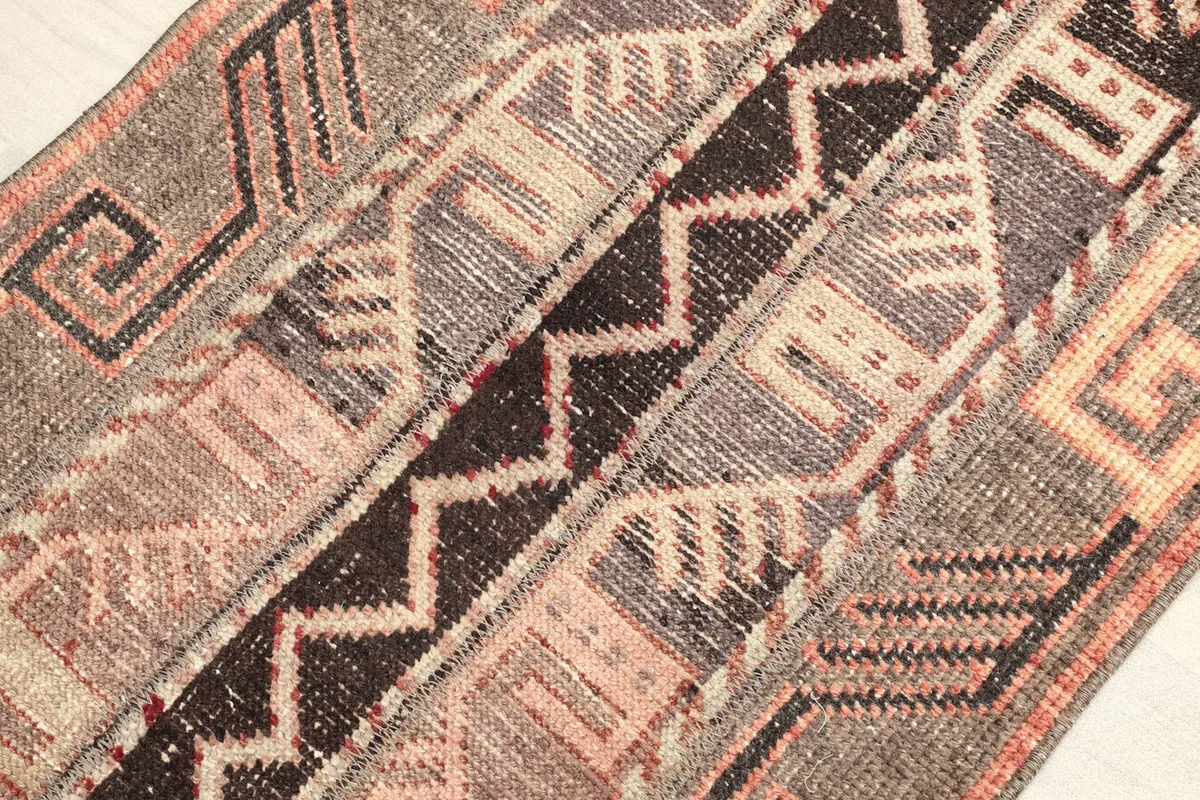Detailed view of the rug's central brown and beige tribal patterns and zig-zag motifs.