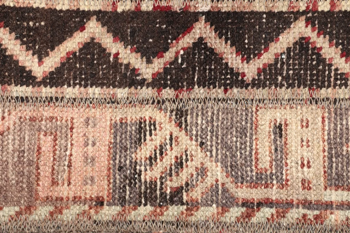 Close-up of the intricate geometric motifs and color variations in the rug's pile.
