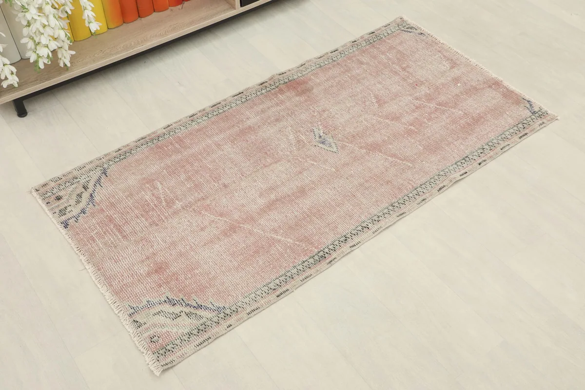 Angled view showcasing the faded rose field and geometric border of the hand-knotted rug
