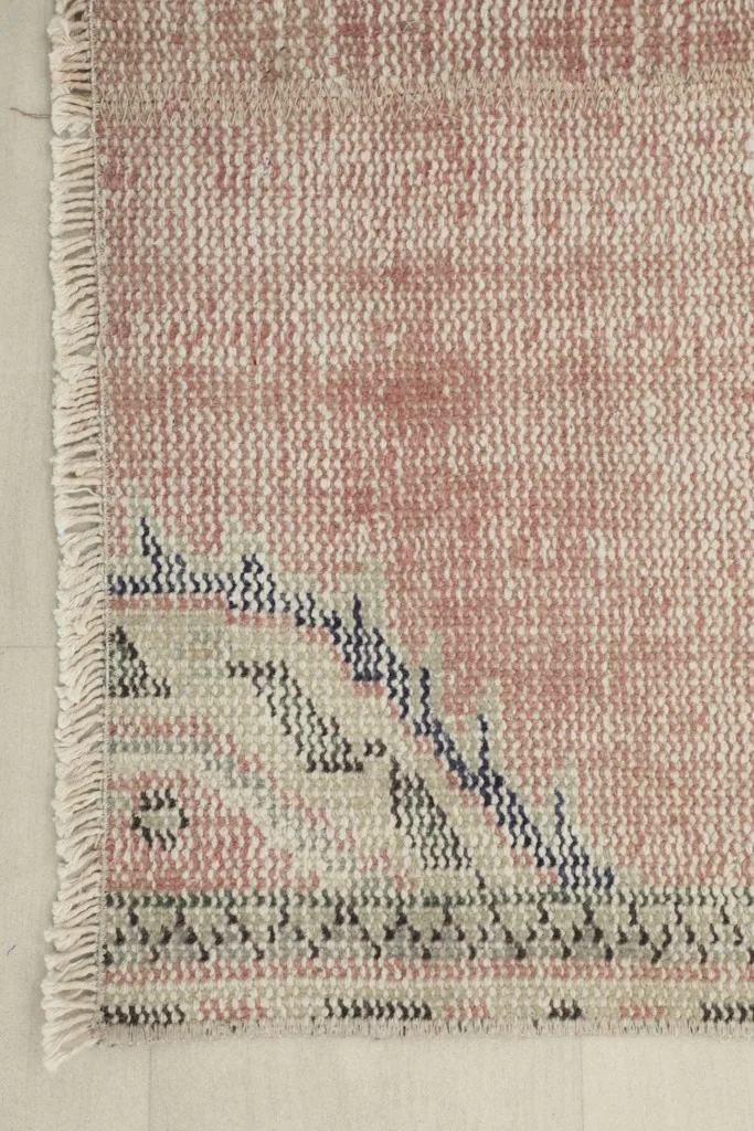 Close-up of the rug's corner, highlighting the blue and gray geometric border design and fringe