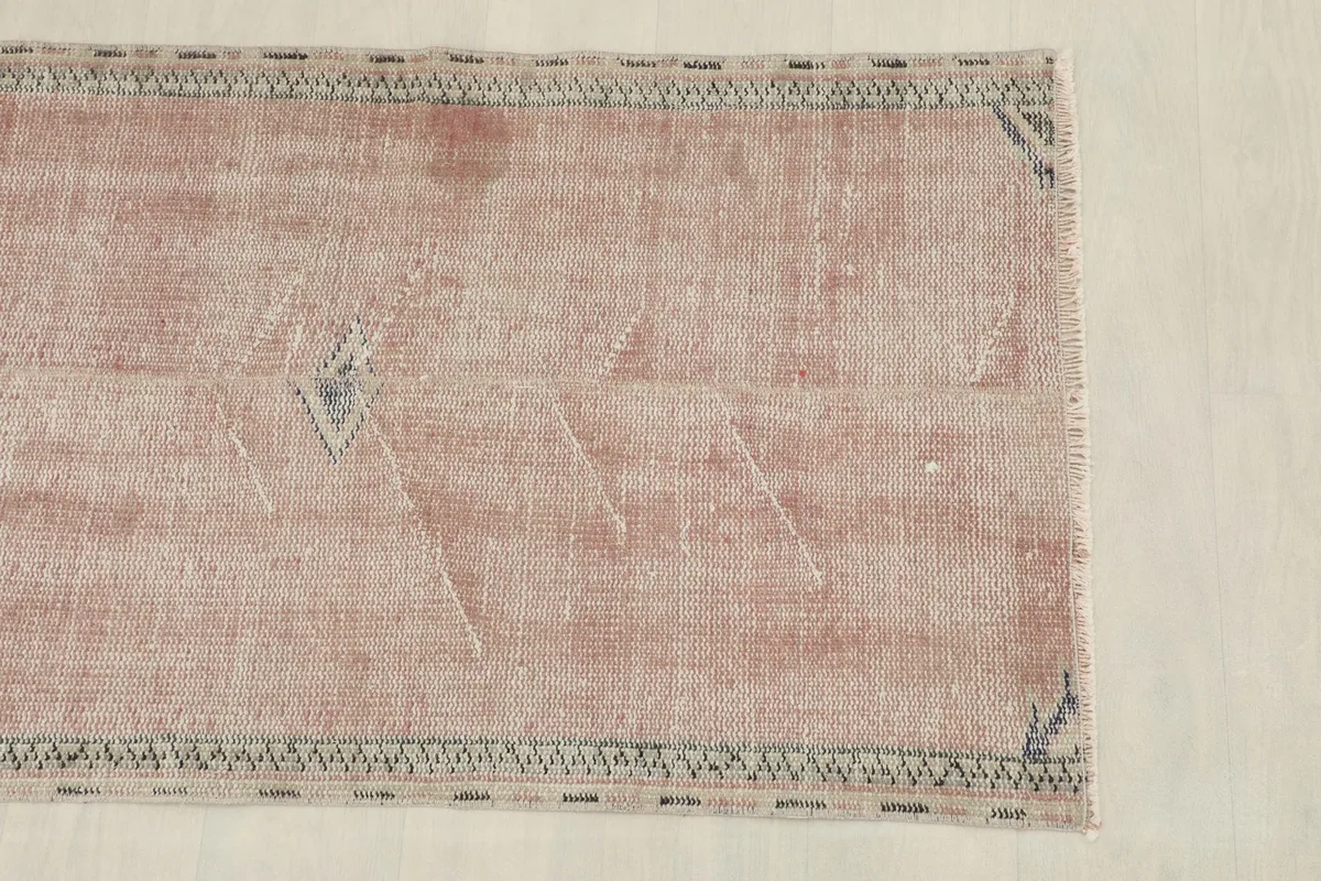 Overhead view focusing on one half of the rug, showing the faded rose field and border