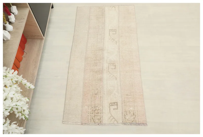 Full overhead view of the beige and tan patchwork vintage Anatolian rug on a white floor