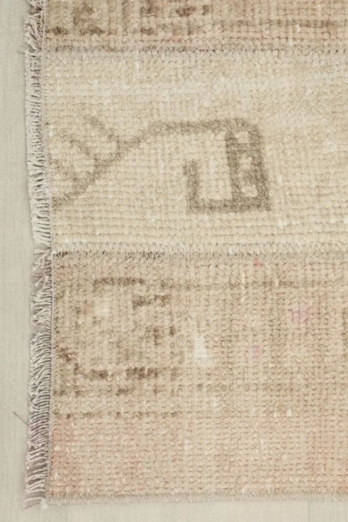 Close-up showing the edge of the rug, revealing a patchwork seam and subtle fringe details