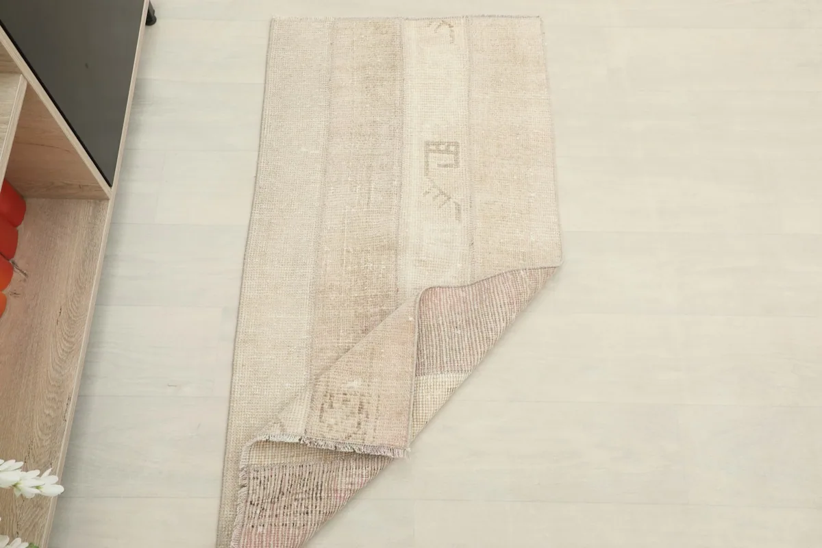 The beige patchwork rug shown partially folded, indicating its flexibility and thickness