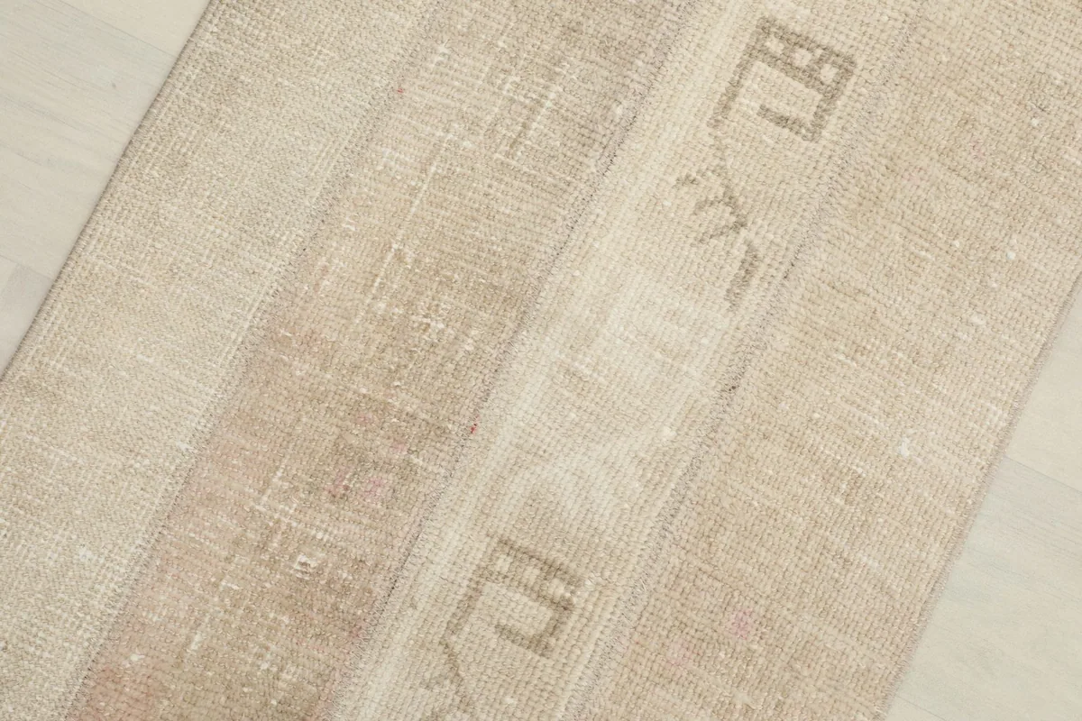Close-up overhead view of the rug's surface, highlighting the different beige and tan patches and textures