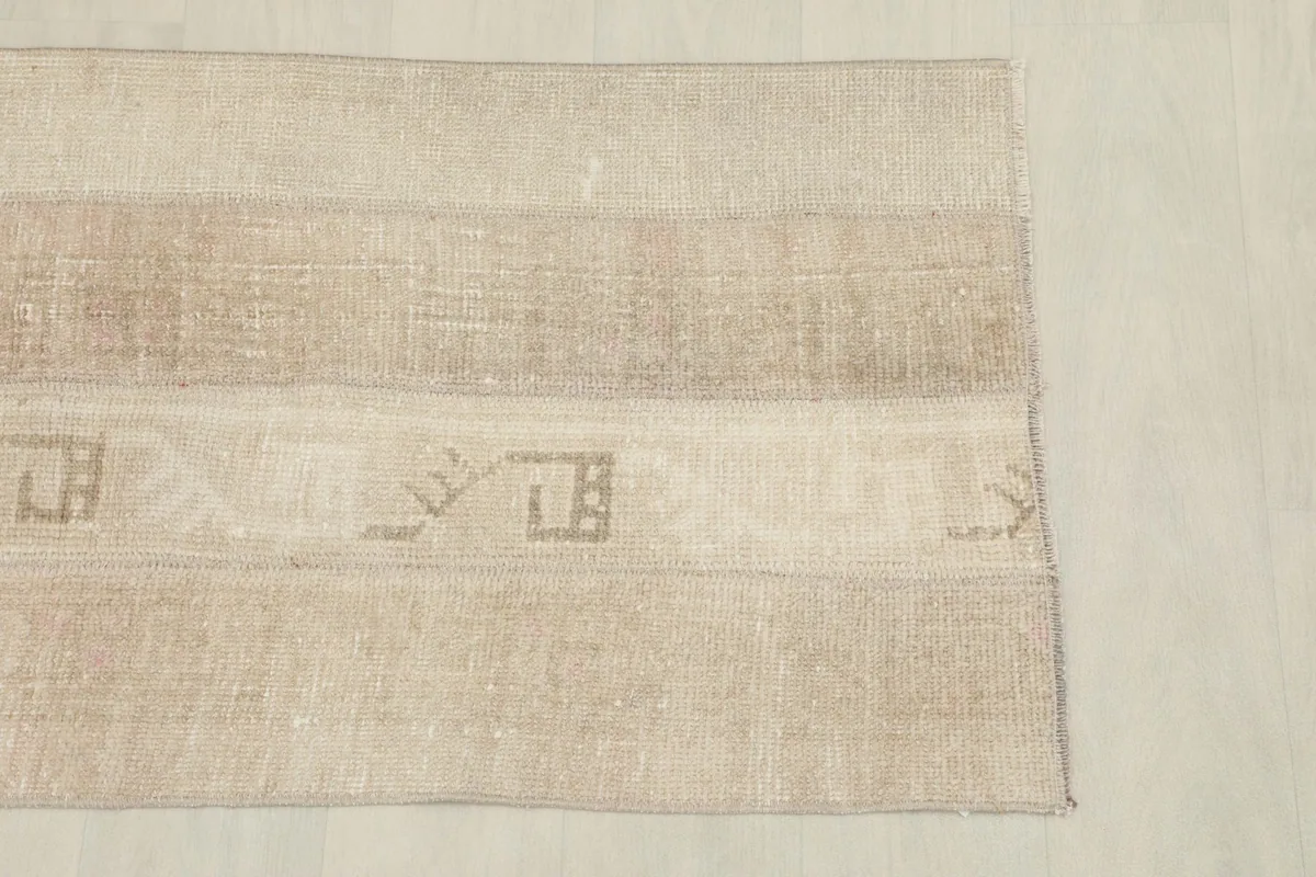 Overhead view of one end of the rug, displaying the horizontal patchwork strips and embedded motifs