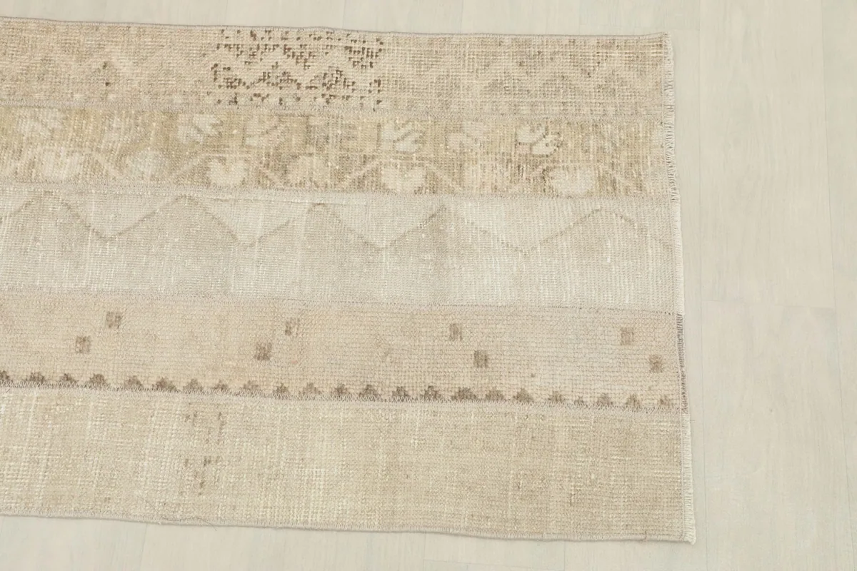 Top-down view of one end of the rug, showing the blend of patterned and plain beige panels