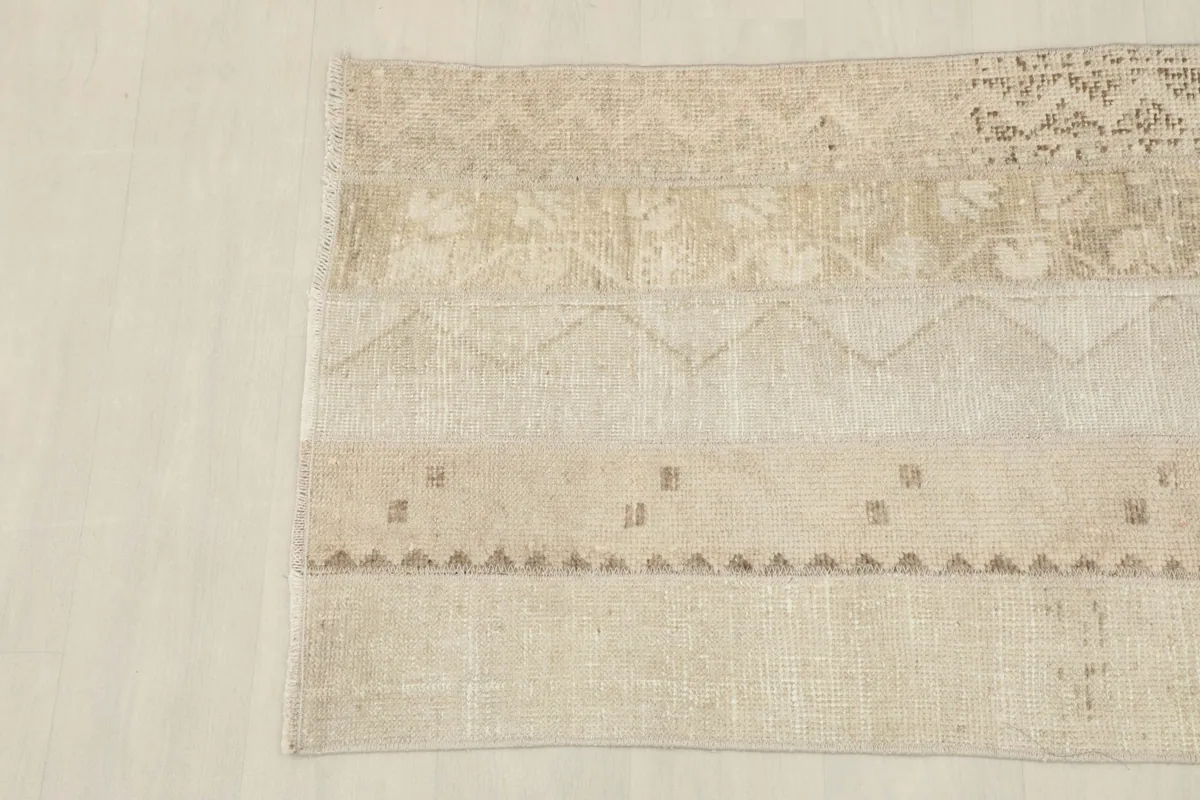 Angled shot of the other end of the rug, emphasizing the overall neutral palette and design