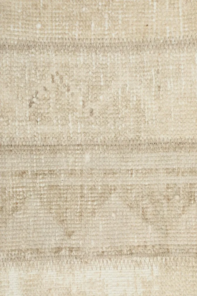 Macro detail of the subtle geometric motifs woven into the beige wool pile of the rug