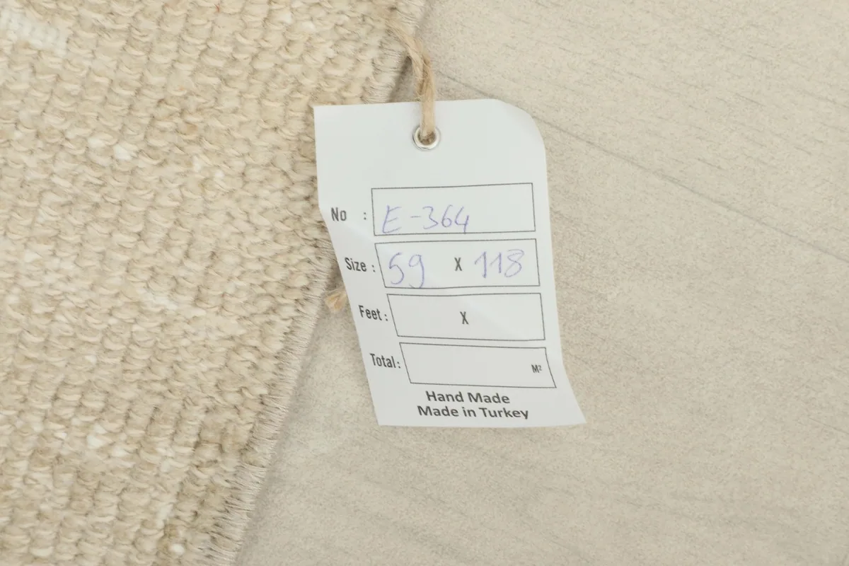 Close-up of the product tag indicating the rug's size in centimeters and its handmade origin