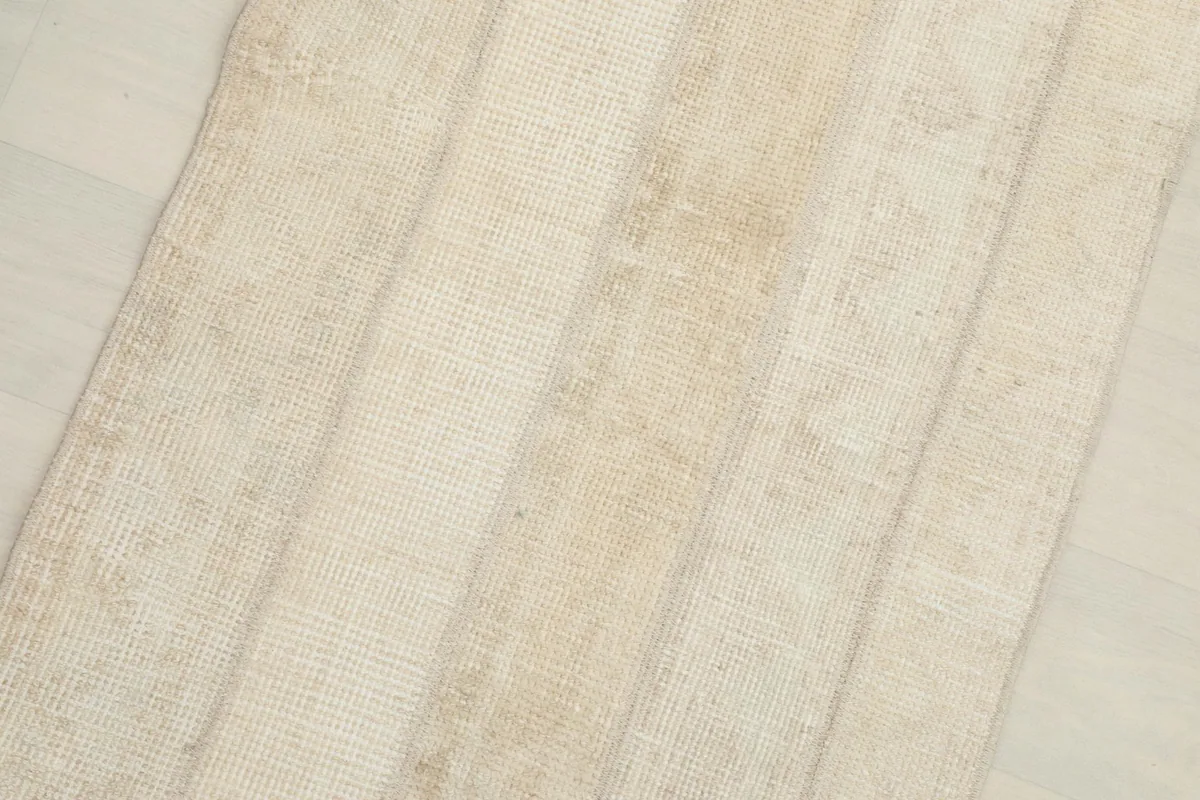 Close-up view of the rug's surface, highlighting the variations in beige tones and textured weave.