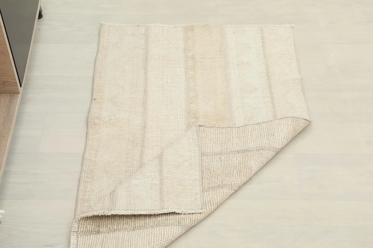 The rug partially folded, showing both the pile and the reverse side with its structured foundation.