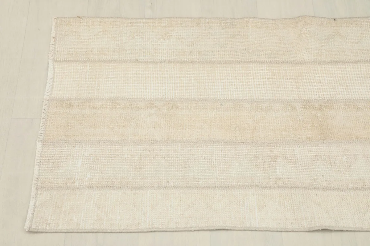 Overhead view showing the length of the rug and its consistent beige and ivory striped pattern.