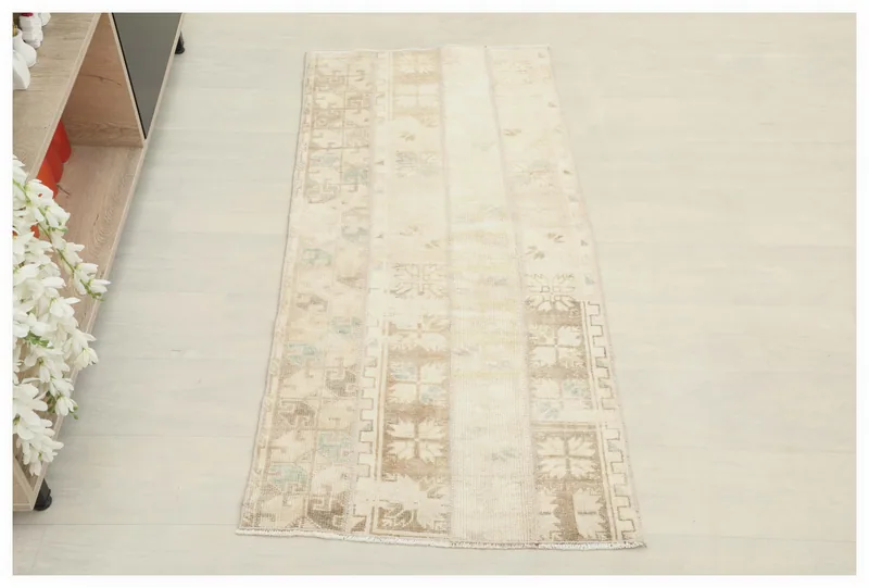Full top view of the beige and brown patchwork vintage area rug on a white floor