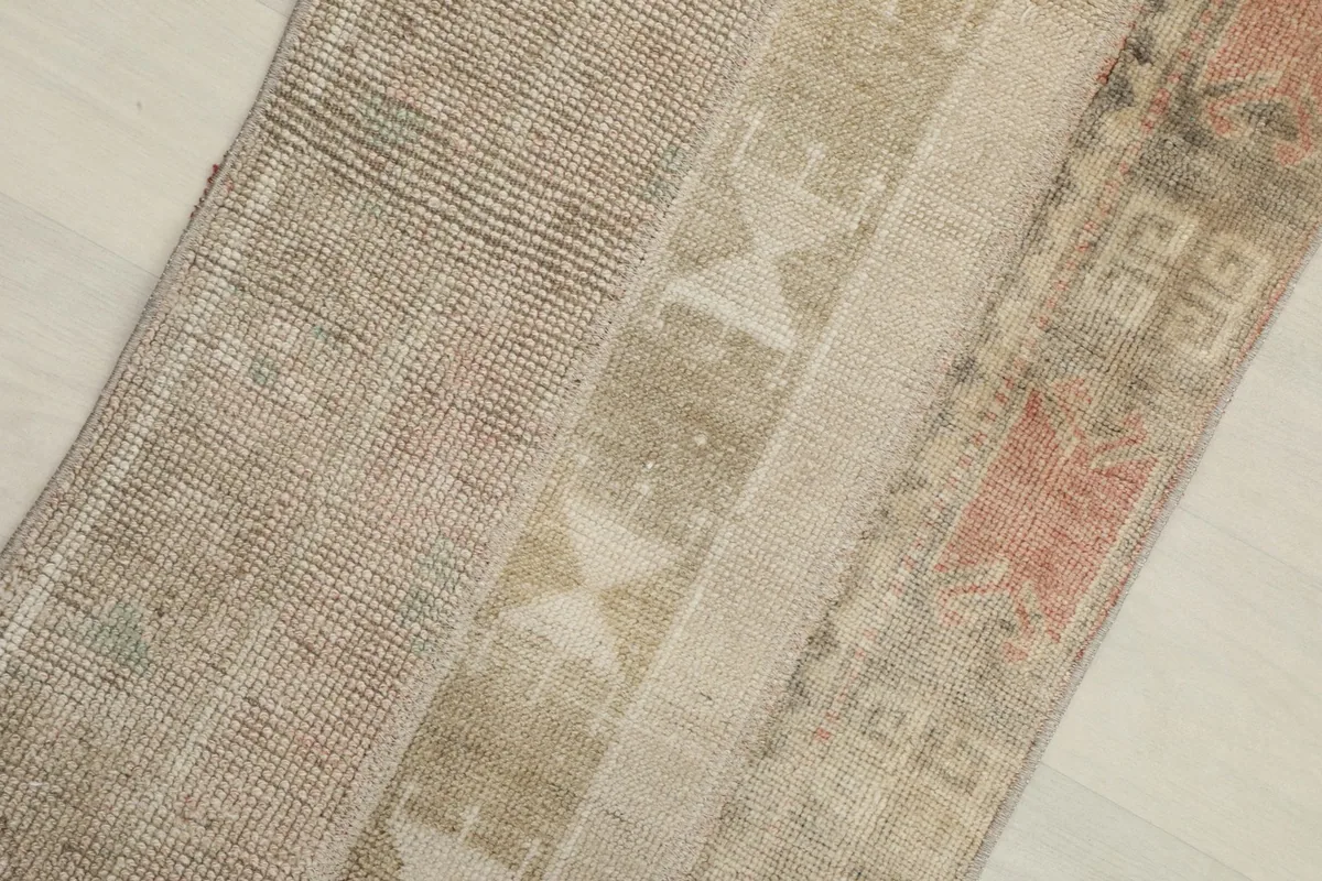 Close-up detail of the rug's surface, highlighting the geometric patterns and muted beige, gray, and rust colors.